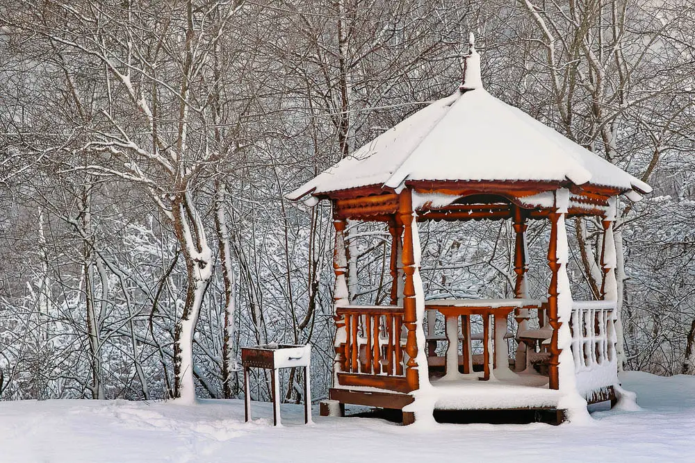 While this gazebo flaunts its rustic charm, with rich wood tone and ornately carved columns we see it bringing a spot of warmth and brightness to the stark winter landscape. Even covered by snow, it stands out with its welcoming curves and built-in table at the center, surrounded by built-in bench seating.