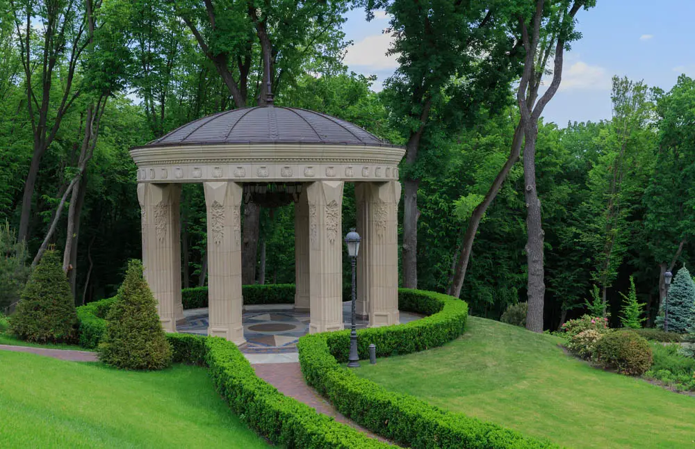 Alright, let's be honest. This gazebo isn't exactly meant for the average home or garden. It's an astounding piece of sculpture, a massive stone structure on intricately carved pillars, hanging over a grand marble floor design. The domed roof centers on a spike, and the entire structure is wrapped by neatly manicured bushes. It might be too rich for our blood, but it's inspirational nonetheless.