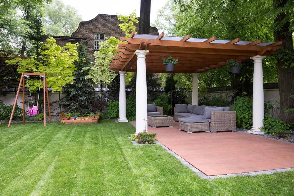 We love this gazebo because, despite its completely open-to-the-sides design, it's a beautiful way to relax and enjoy sheltered space in the outdoors. The four ornate white pillars support a natural wood upper structure, hung with potted plants and canvasing a detached patio wrapped in brick. There's plenty of room for an entire outdoor set of comfortable furniture in here.