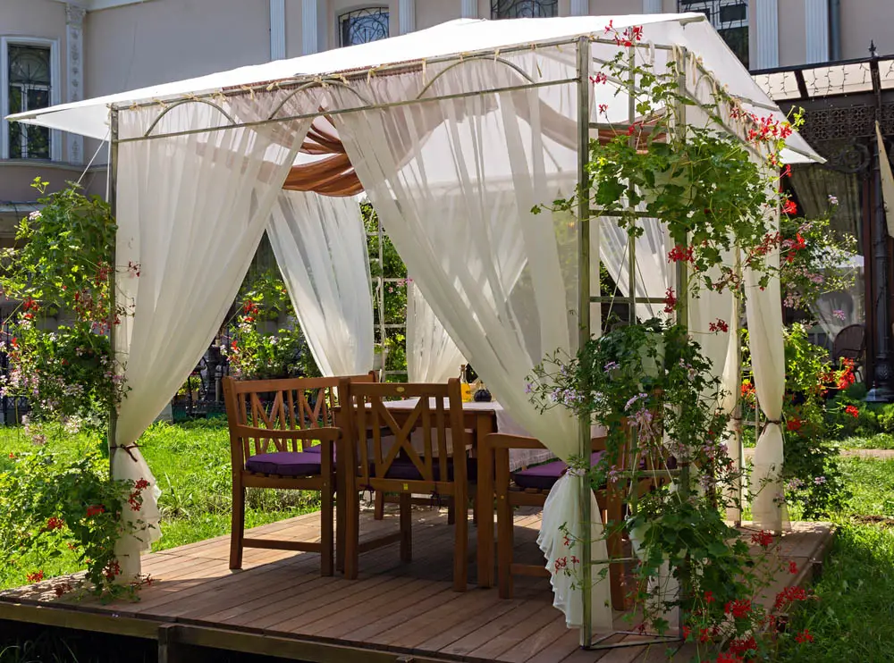 If having a thick, solid structure isn't the most important thing to you, a thinner metal gazebo might be the perfect fit. This model features trellis-like supports designed to hang flower baskets, and can be placed virtually anywhere because of its light weight. Here we see it set atop a rich wood base, but a gazebo like this can be planted right in your garden.