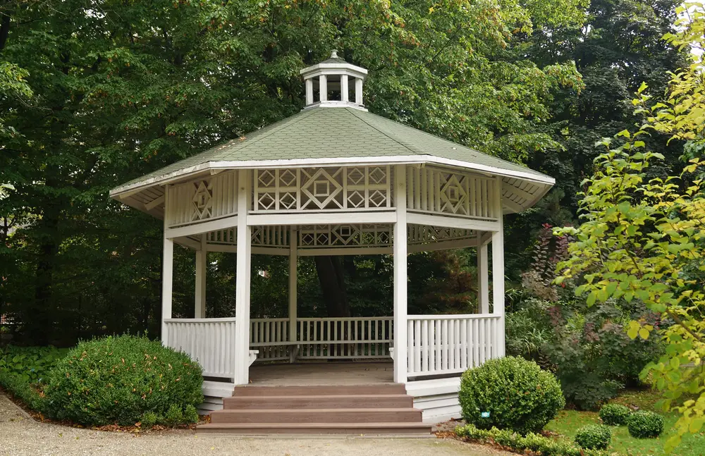 Similar to one of the more ornate gazebos pictured above, this gorgeous white model features intricate designs in the wood spanning between pillars. The geometric shapes give it a unique presence among other similarly built gazebo structures, while the small dome on the top of the roof adds another instance of intrigue. We love the wraparound bench seating built inside.